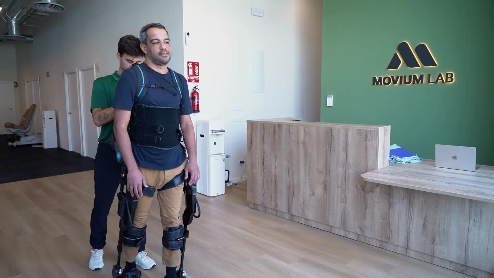 Persona con exoesqueleto junto a su fisioterapeuta en la recepción de Movium Lab